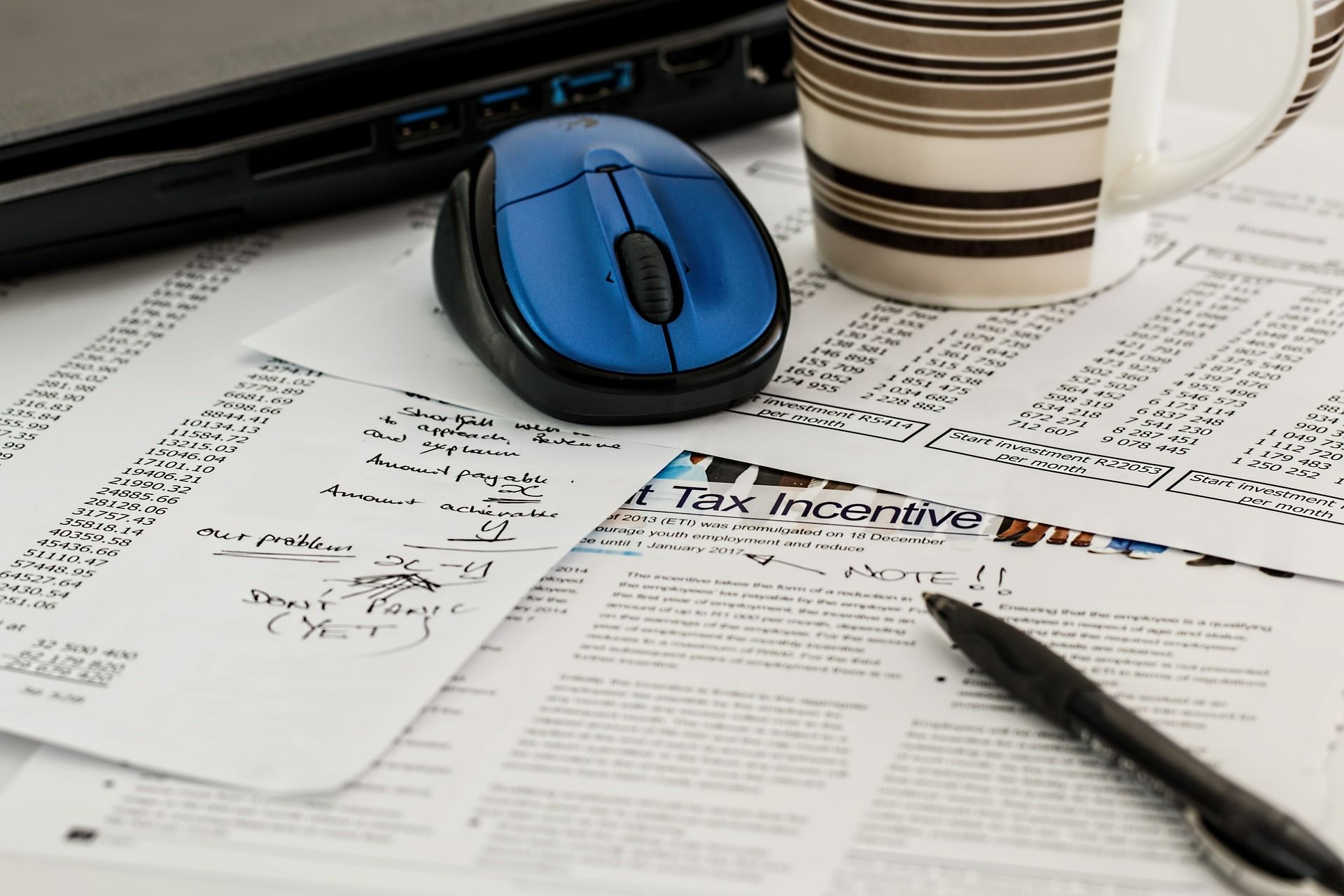 pen, mouse and mug on top of documents